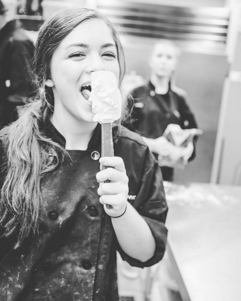 Student chef licking spatula at culinary arts summer cooking camp